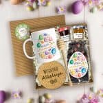 Otwarty box wielkanocny z kubkiem, herbatą, miodem, konfiturą i drewnianym miodownikiem na jasnym tle