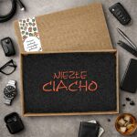 Czarny ręcznik z haftem \"Niezłe ciacho\" w otwartym pudełku z szarfą