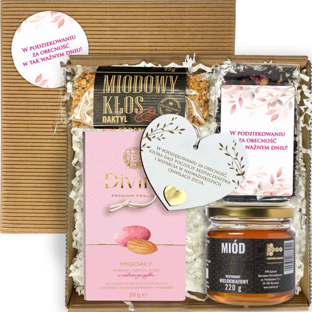 Otwarty box komunijny z herbatą, miodem, batonem, migdałami i zawieszką serce