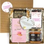 Otwarty box komunijny z herbatą, miodem, batonem, migdałami i zawieszką serce