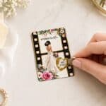 Pogrubiona karta z nadrukiem przedstawiającym pannę młodę od tyłu, ozdobiona kwiatami i ramką przypominającą taśmę filmową. Na karcie widoczny napis 'WYKONAM DLA MĘŻA...' oraz złote serce ze zdrapką z tekstem 'KAWĘ DO ŁÓŻKA'. Ręka trzyma monetę przy zdrapce.