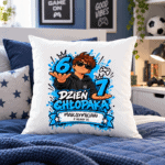 Biała poduszka na granatowym łóżku z ilustracją chłopaka w okularach, niebieskimi cyframi 6 i 7 oraz napisem „Dzień Chłopaka”.